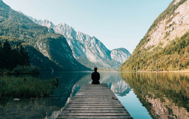 Traveller sitting on a dock over an alpine lake